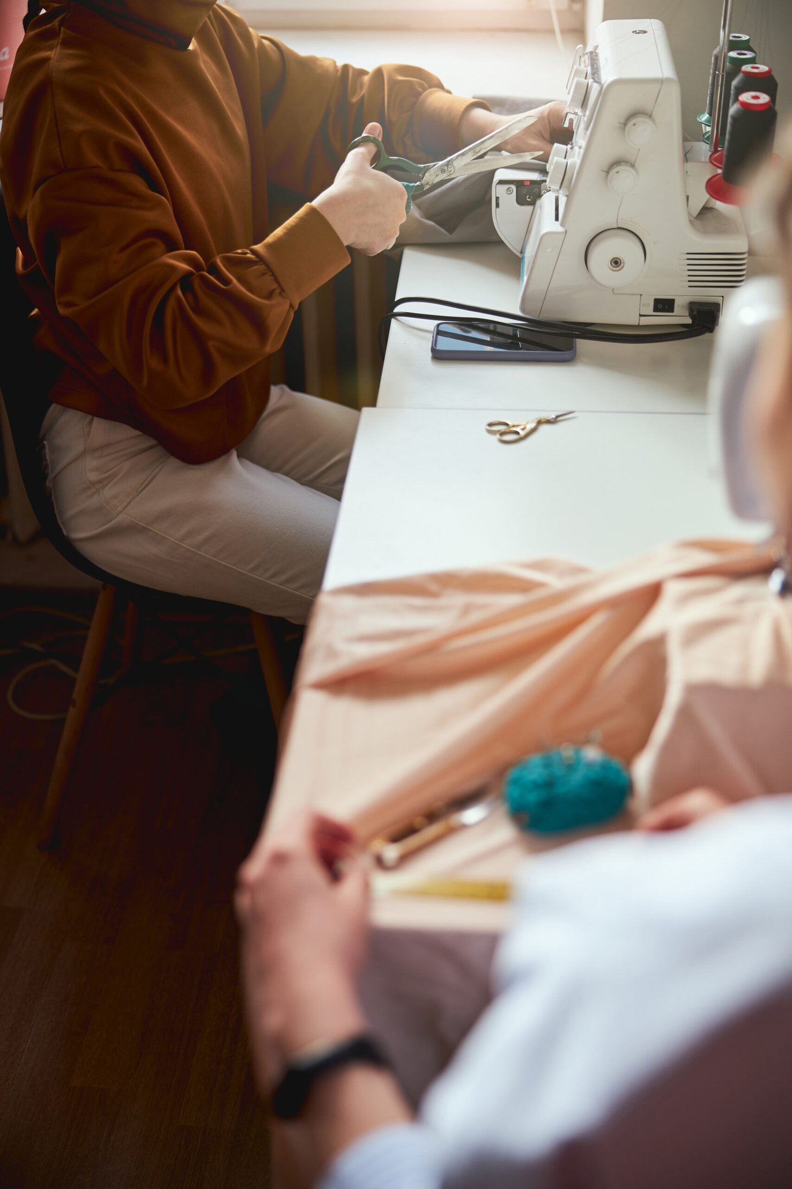 Person near window reaching to thread with crafting scissors