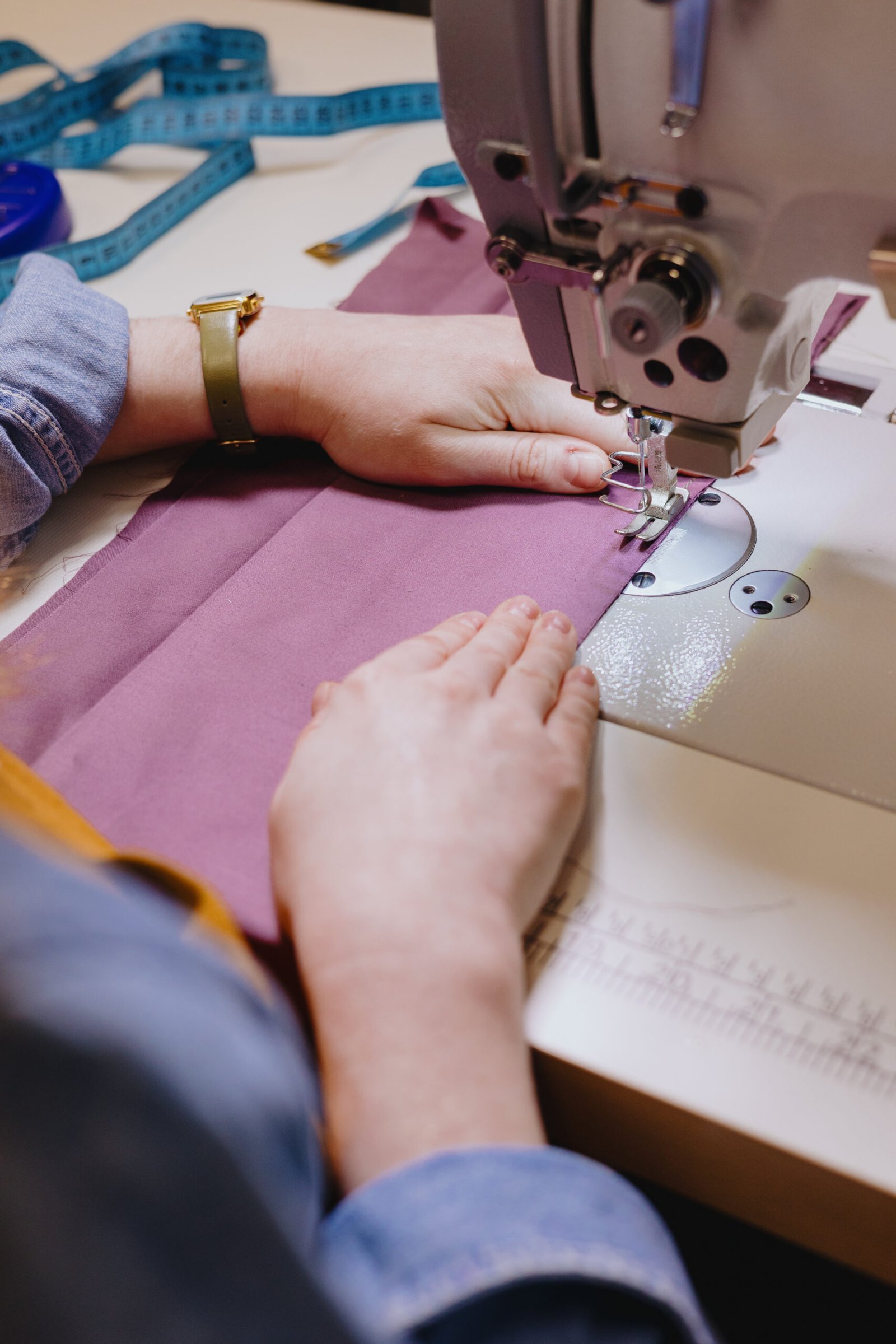 woman sews piece of cloth on sewing machine. industrial metal machine for all fabric tops.